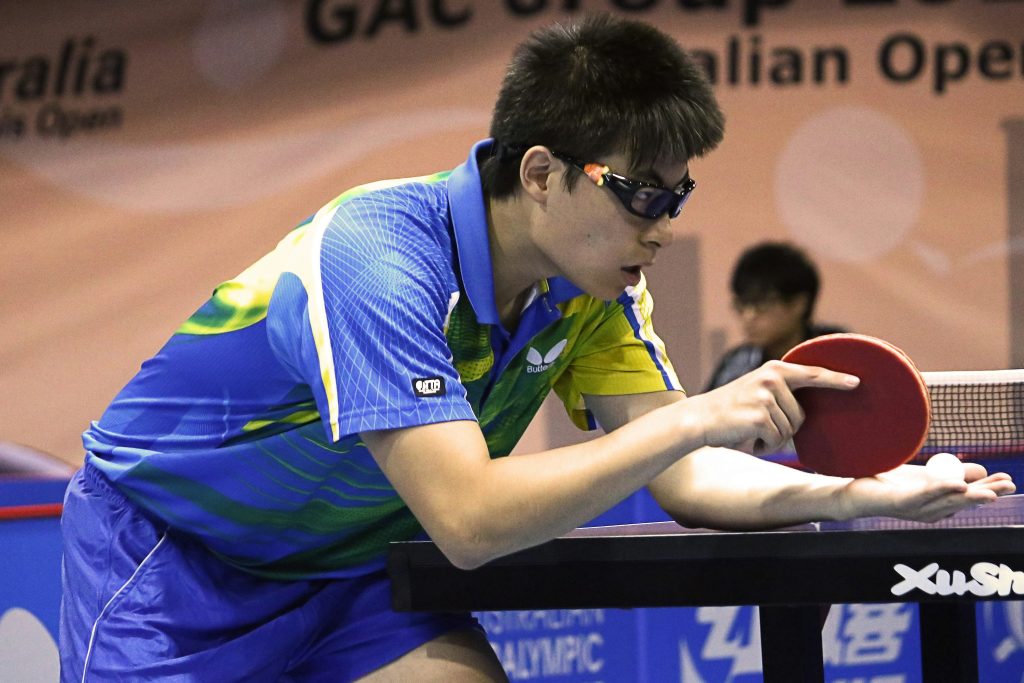 A focused table tennis player in a colorful Butterfly uniform prepares to serve, showcasing elite talent from one of the best table tennis clubs in China.