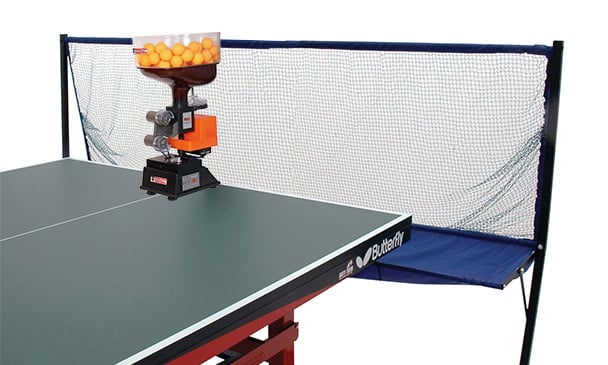 Butterfly table tennis robot with ball feeder and net catcher set up on a green table for solo practice sessions.